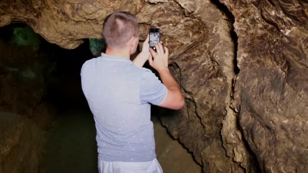 Kerel toerist neemt foto 's van grotten in de kerker. — Stockvideo
