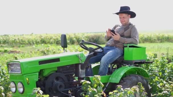 Venkovský farmář sedí na zeleném traktoru a listuje v sociálních sítích.. — Stock video
