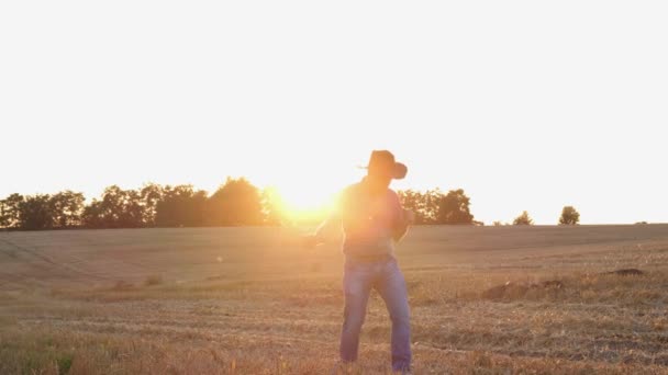 Glad byarbetare dansar på en äng vid solnedgången. — Stockvideo