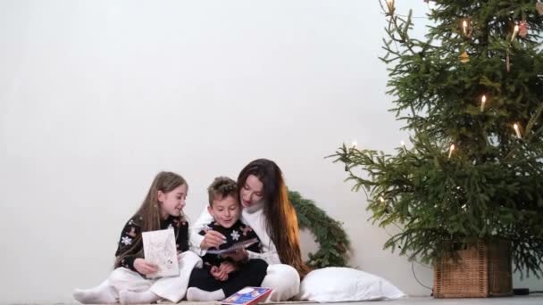 Glückliche Familie am Weihnachtsbaum, sie sitzen und kommunizieren miteinander. — Stockvideo