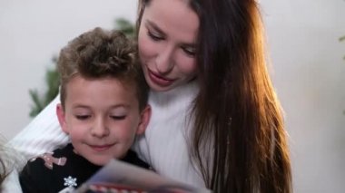 Anne ve çocuklar kitap okurlar, birlikte gülerek eğlenirler..