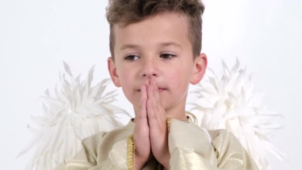 Petit garçon aux ailes d'ange, il prie sincèrement dans le temple. — Video