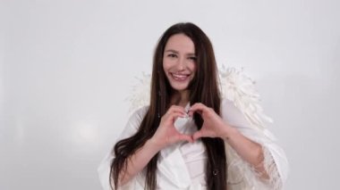 Melek kanatlı güzel esmer elleri ile kalp şeklini gösterir.