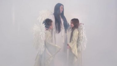 Anne ve çocuklar dumanda melek kanatlarıyla. 