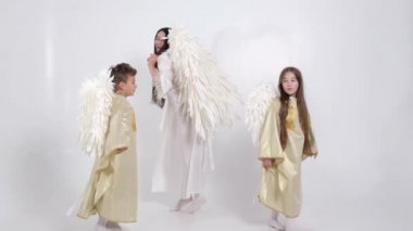 Duman içinde beyaz bir arka planda melek kanatlarıyla dans eden aile. 