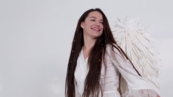 Brunett flicka med ängel vingar dansar på en vit bakgrund. — Stockvideo