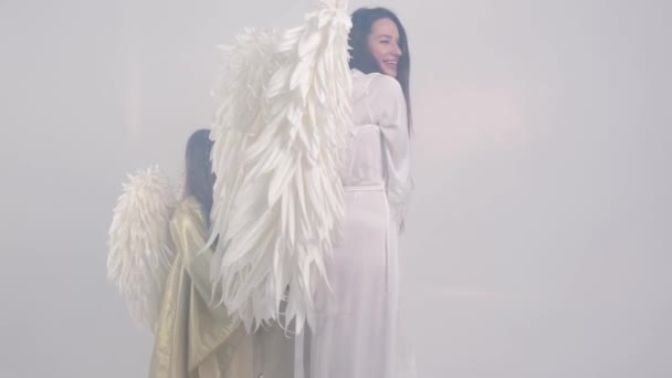 Danse de famille avec des ailes d'ange sur un fond blanc en fumée. — Video