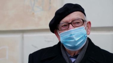 Virüs bulaşmasın diye açık havada tıbbi maskeli yaşlı büyükbaba..