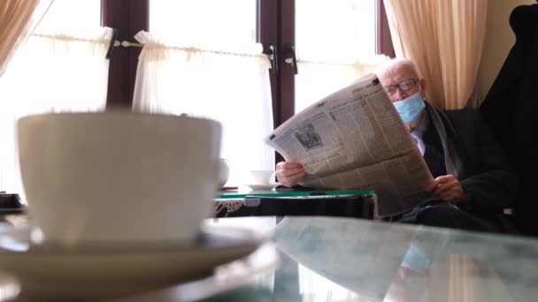 Um pensionista em uma máscara protetora lê a imprensa. — Vídeo de Stock