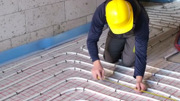 Un trabajador profesional organiza la calefacción de agua en el suelo de la casa. — Vídeo de stock