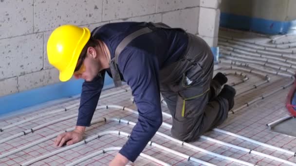 Um encanador profissional instalar um piso aquecido. Instalação de tubos de encanamento. — Vídeo de Stock