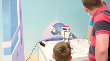 Baba ve küçük oğlu Exhibitio 'da modern bir robotla konuşuyor.