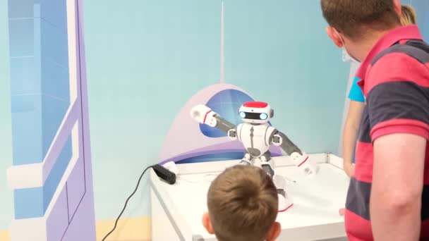 Pai e filho jovem conversando com um robô moderno na exposição — Vídeo de Stock