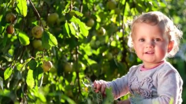 Şirin küçük kız yeşil bahçede oturmuş oynuyor..