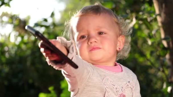 Vacker blond baby hålla och titta på smartphone. — Stockvideo