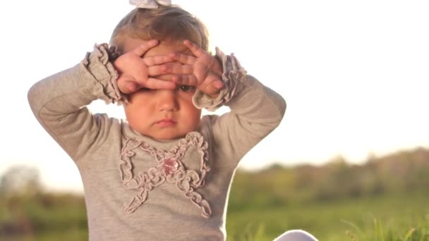 Belle blonde bébé assis à l'extérieur dans le jardin de la cour par une journée d'été ensoleillée. — Video