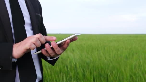 Homem de negócios trabalhando em um tablet em um campo verde. — Vídeo de Stock