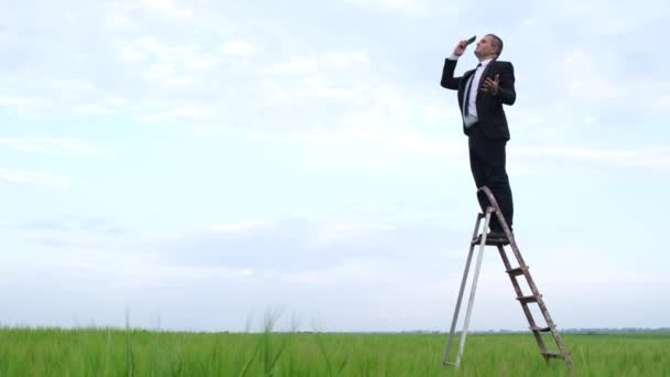Een man vangt een mobiel netwerk in een open veld — Stockvideo