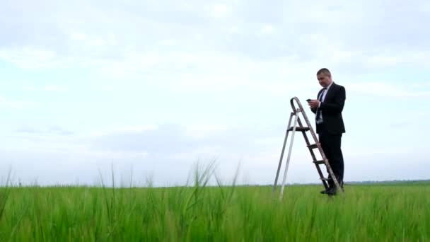 Young businessman in the middle of the field looking for internet connection. — Stock Video