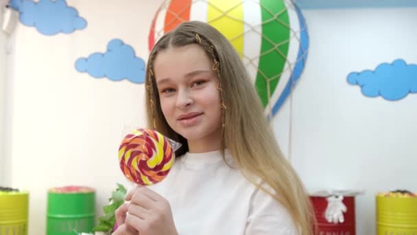 Usmívající se krásná holčička s barevnými lízátka na klacku v cukrárně. — Stock video