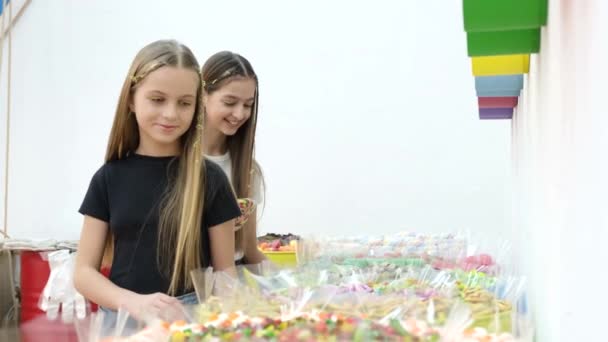 Roztomilé dospívající dívky se těší na pestrobarevné bonbóny a lízátka. Touha po sladkostech. — Stock video
