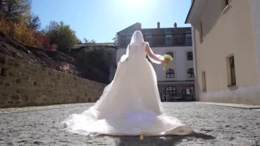 Gelinin elinde bir buket çiçekle güzel, lüks bir elbise içinde koşuyor.
