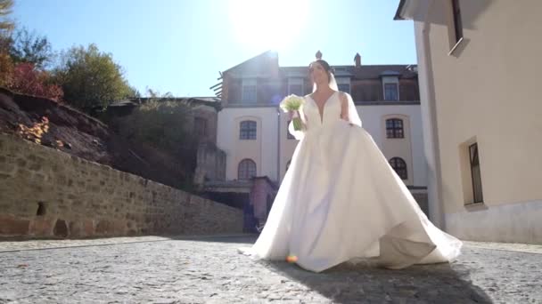 Die Braut in einem wunderschönen Kleid mit einem Blumenstrauß in ihren Händen — Stockvideo