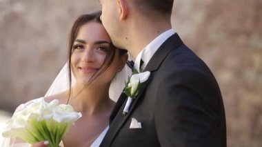 Damat gelini nazikçe kafasından öper. Sevgili genç bir çiftin portresi..