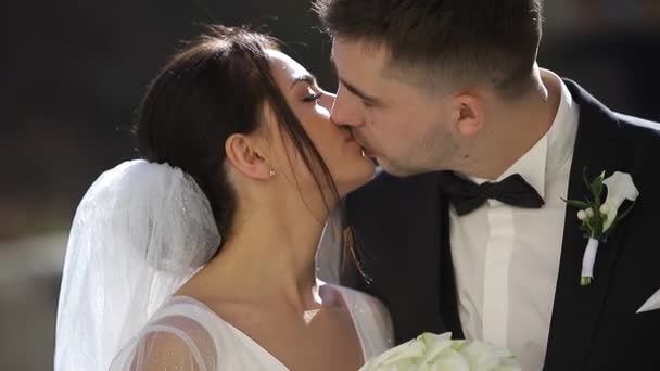 Close up de um jovem casal se beijando, eles são lindamente iluminados pelo sol. — Vídeo de Stock