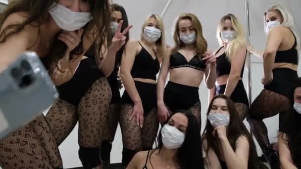 Sexy meisjes in beschermende maskers nemen selfies op een smartphone. dansgroep in sexy kleren. — Stockvideo