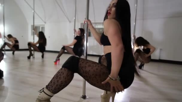 En grupp sexiga tjejer i svarta underkläder som dansar på en påle i en dansstudio. Dansar på pylonen. — Stockvideo