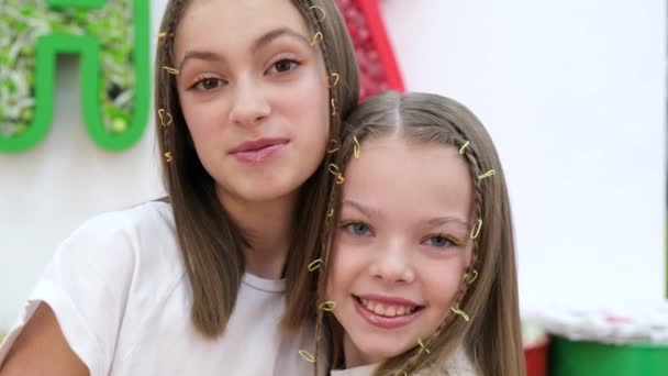 Porträtt av två systrar som kramas och skrattar glatt. Tonåringar på en färgstark bakgrund. — Stockvideo