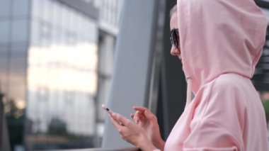 Genç bir kız pembe bir ceket giymişti. Bildirimler için akıllı telefon kullanıyordu..