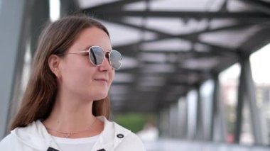 Güneş gözlüklü güzel esmer kız başka tarafa bakıyor. Şık ve şık bir kız.