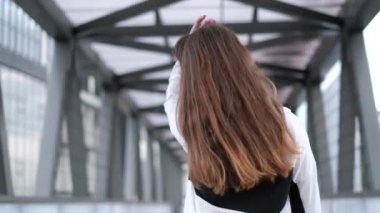 Uzun saçlı bir kız şehrin sokaklarında mutlu mesut dolaşıyor ve gülüyor.