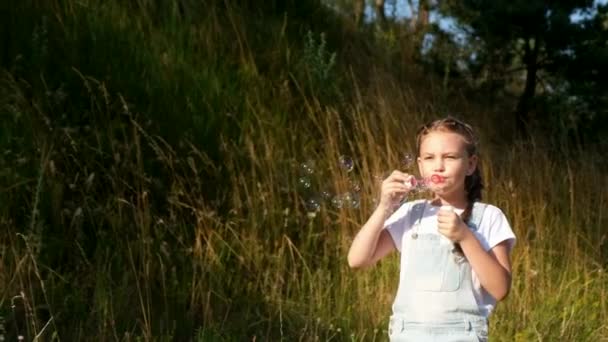 The little girl goes and blows bubbles. A child in a summer camp. — Stock Video