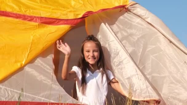 Campo de férias de verão. Uma menina abre uma tenda amarela, ela está descansando nas férias de verão. — Vídeo de Stock