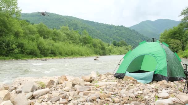 산에 있는 강 근처에 있는 천막 위를 나는 드론. — 비디오