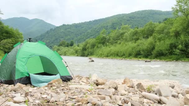 Hermoso terreno de montaña, y una carpa verde junto al río. — Vídeo de stock