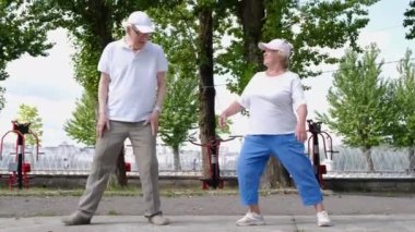 Emekli bir aile parkta sabah sporu yapıyor. Büyükannem ve büyükbabam spor yapar..