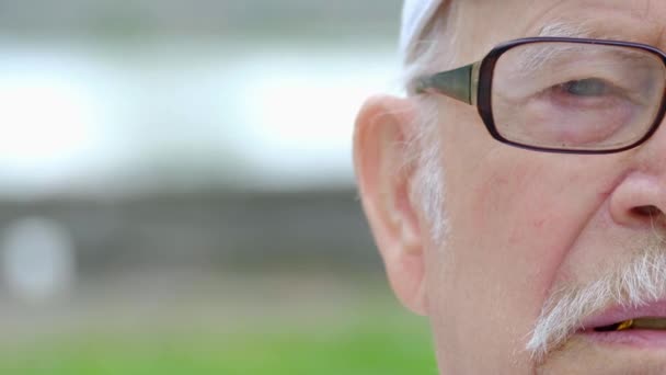 Metade do rosto de um velho avô deprimido de perto, ele é cinza e usando óculos — Vídeo de Stock