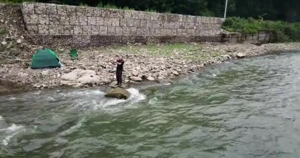 Рыбак-самец ловит рыбу на бурной горной реке, вращая хищную рыбу.. — стоковое видео