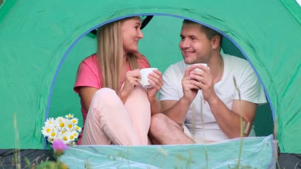 A loving couple is resting in the mountains, they are sitting in a tent and talking. Budget tourists — Stock Video