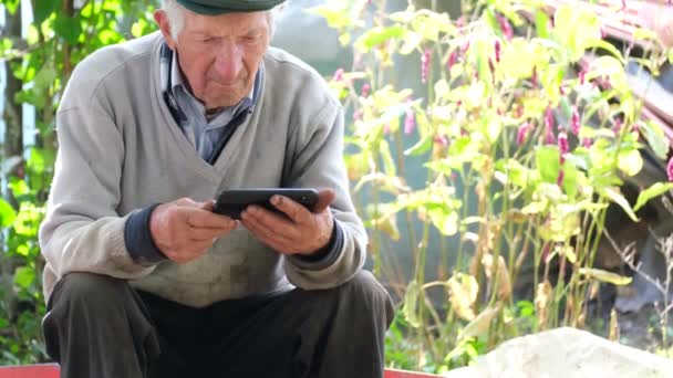 Älterer Mann sitzt mit Handy allein im Freien. — Stockvideo