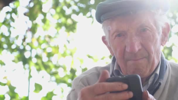 Ο γέρος με μια λυπητερή έκφραση, κρατάει ένα smartphone στα χέρια του.. — Αρχείο Βίντεο