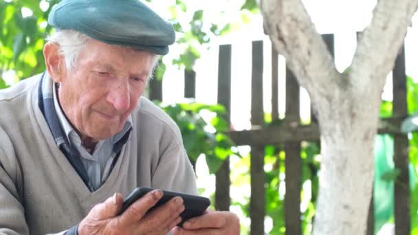 Az öreg nagyapa sír, miközben az okostelefonját nézi. Az Ukrajnával folytatott orosz háború következményei — Stock videók