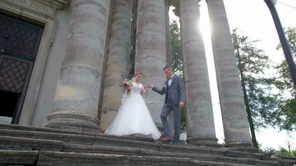 Smukke par brude kramme og kysse nær store søjler i den gamle bydel, bryllupsdag. – Stock-video