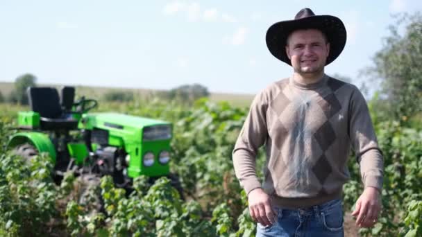 他是美国的一个农业工人，双手交叉地站在田野中央. — 图库视频影像