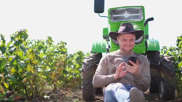 Un agricultor moderno o enólogo habla en un teléfono inteligente durante la temporada de cosecha en el viñedo. — Vídeos de Stock