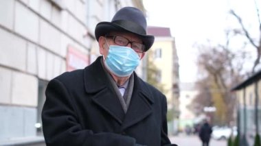 Yüzünde mavi maske olan yaşlı bir adamın portresi, kameraya bakıyor. 